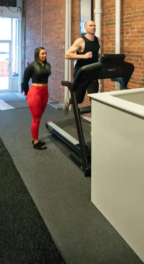 man running on treadmill with fitness instructor on the side